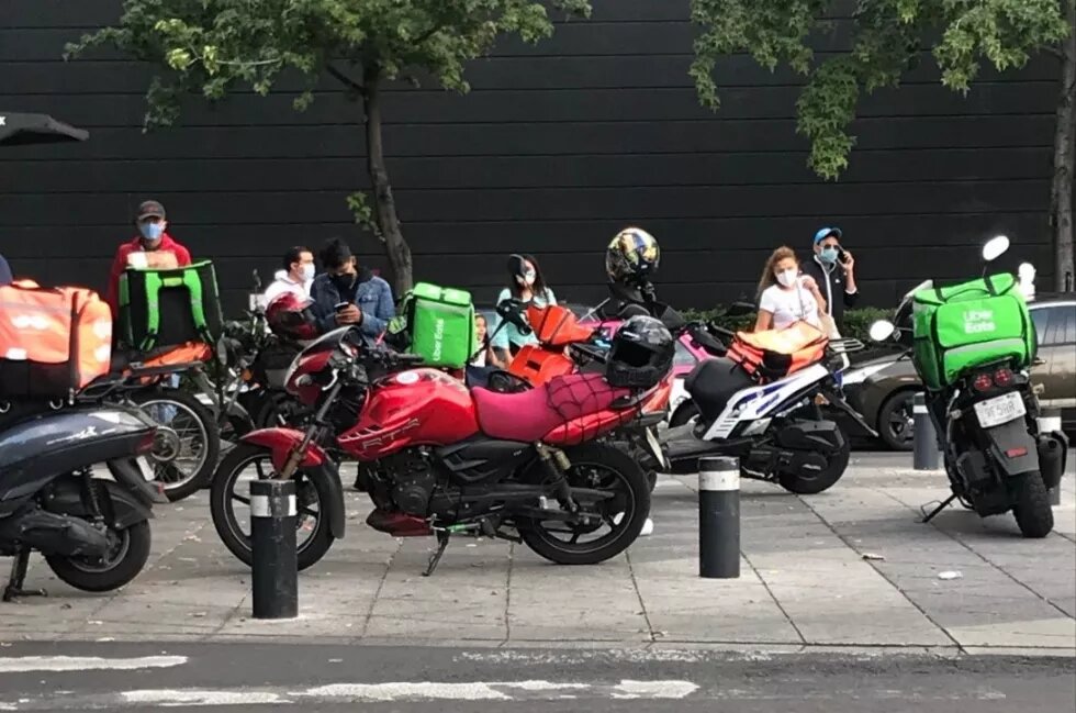 Motorcycle food-app workers waiting an order out of a mall